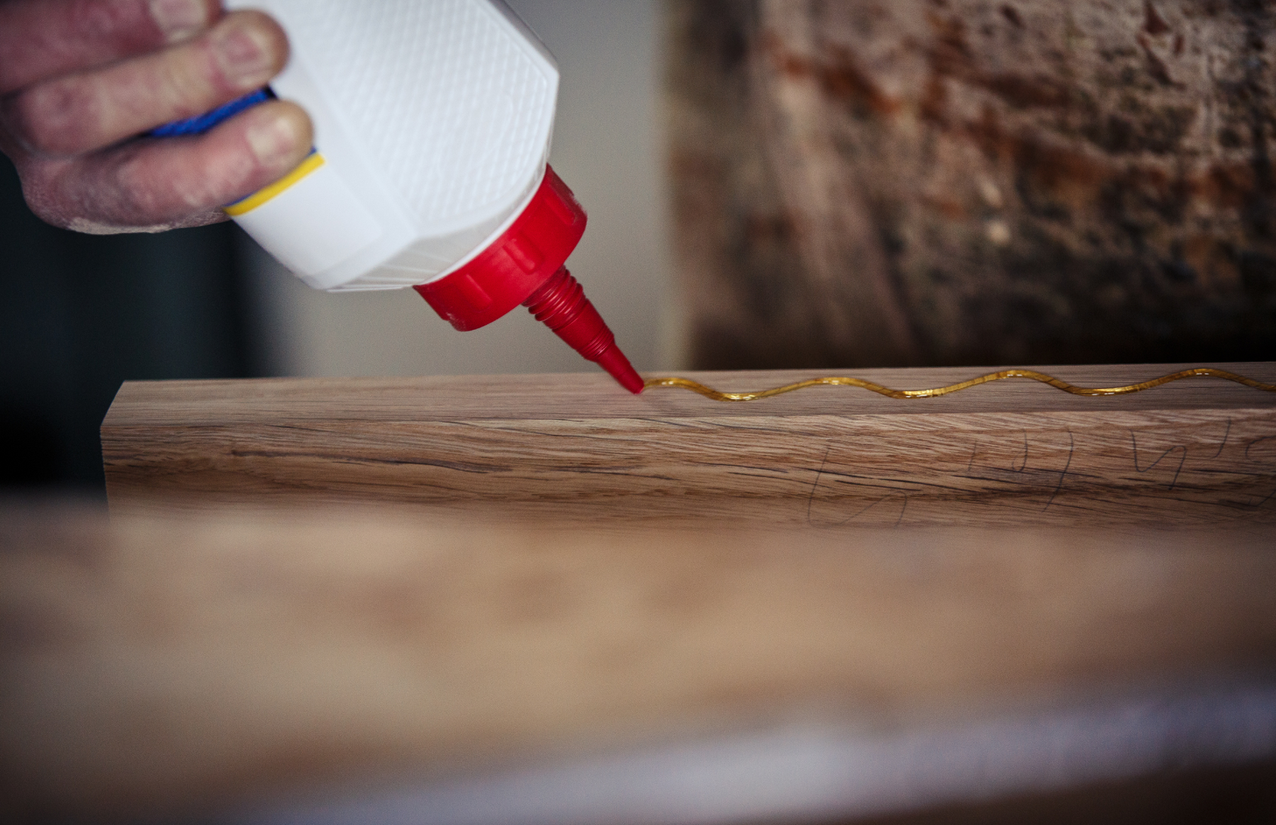 Person applying glue onto wood